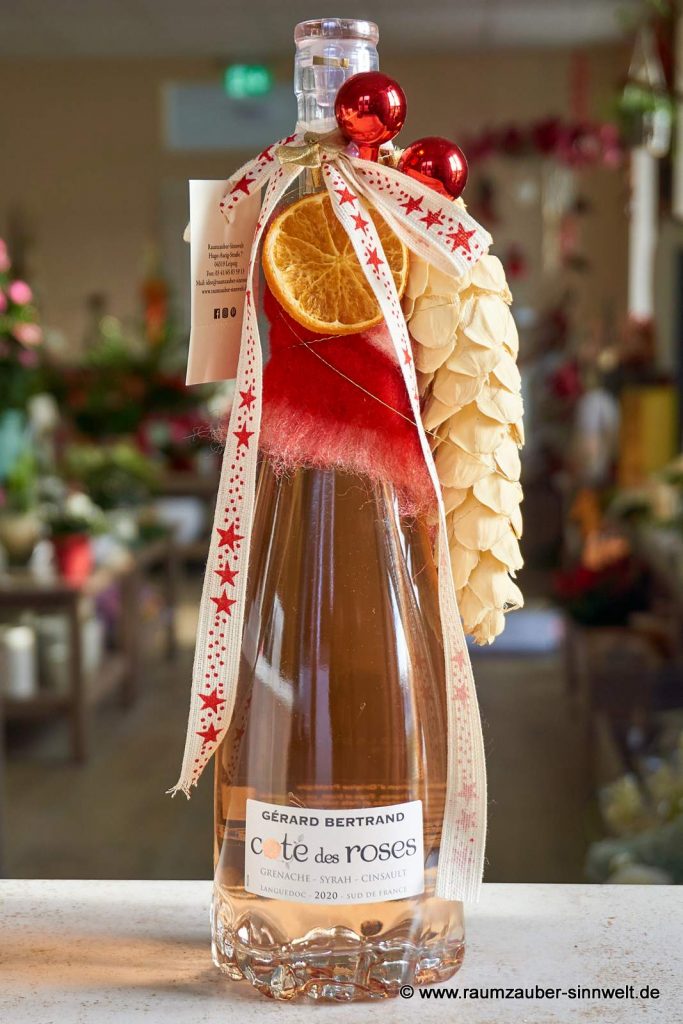Wein "COTES DES ROSES" in der einer Rosenblüte nachempfundenen Flasche mit edlem Glaskorken, aufwendig weihnachtlich dekoriert.