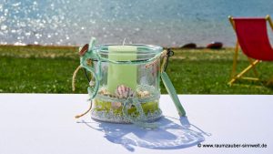 Strandbardekoration mit Muscheln und Kerze im Glas