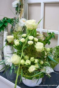 Frischblumengesteck aus Rosen, Panicum und Skelettblättern