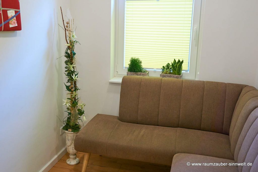 Handgefertigte Seidenblumendekoration mit Naturmaterialien und Grünpflanzen im Steingefäß