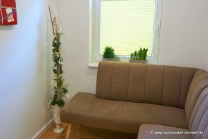 Handgefertigte Seidenblumendekoration mit Naturmaterialien und Grünpflanzen im Steingefäß