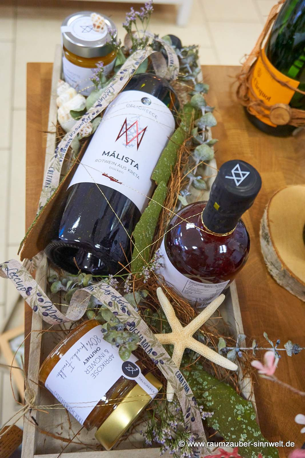 Präsentkorb mit Chutney und Konfitüre aus 85% Frucht, vollmundiger Balsamico aus natürlichen, sonnenverwöhnten Zutaten und Rotwein aus Kreta von Deligreece mediterran dekoriert.