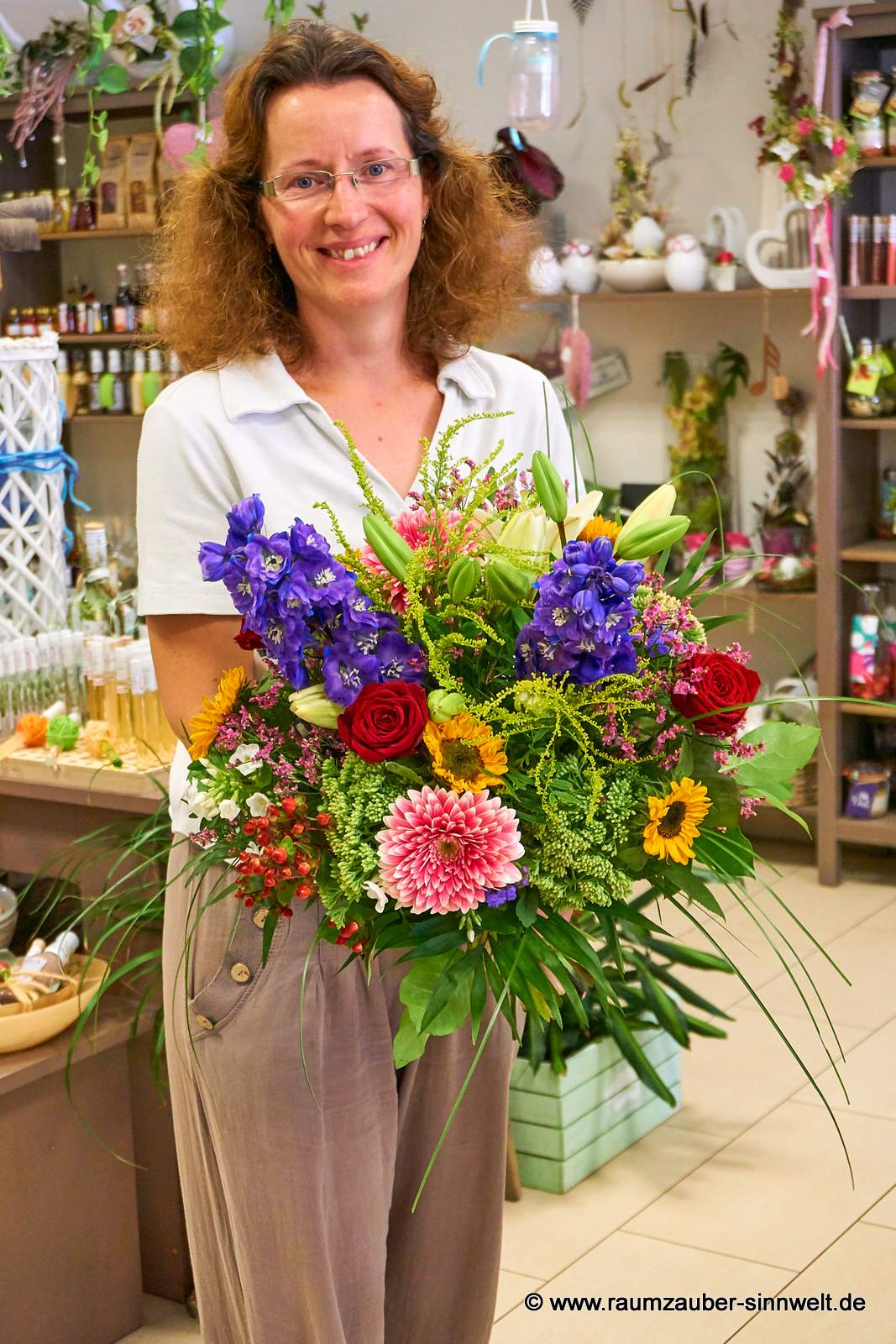 Rundstrauß mit Rittersporn, Gerbera, Sonnenblumen und Lilien.