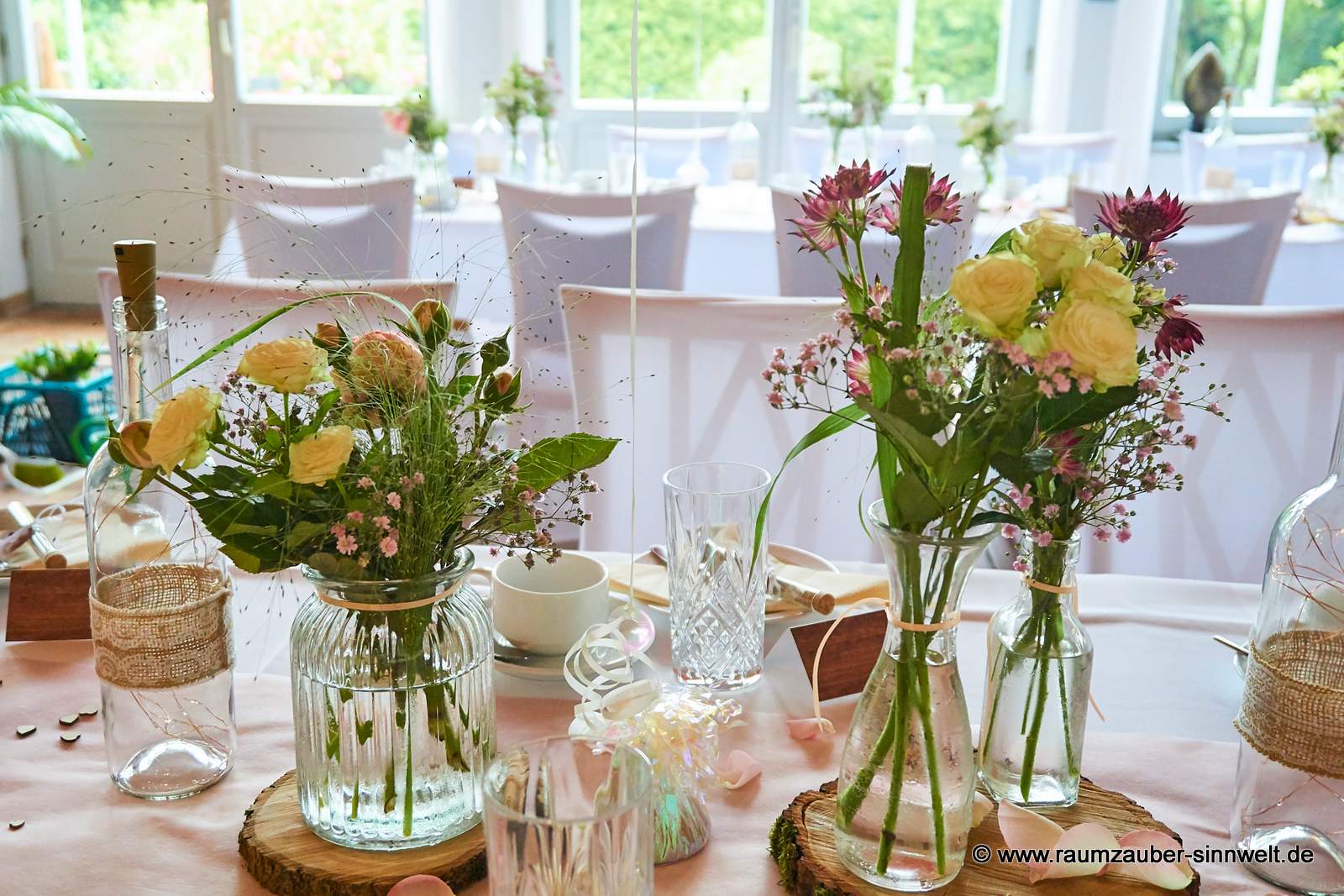 Tischdekoration aus Astrantie, Schleierkraut, Rosen und Gräsern in Gläsern auf Baumscheibe