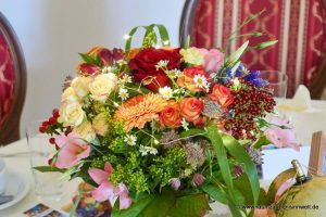Tischdekoration aus Rosen, Gerbera, Kamille, Astrantie, Eustoma, Beeren und Gräsern mit LED-Lichterkette