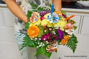 Geldpräsent in Rundstrauß aus Minigerbera, Santini, Bartnelken, Sedum. Alstromerien, Schleierkraut und Stiften zum Schulanfang