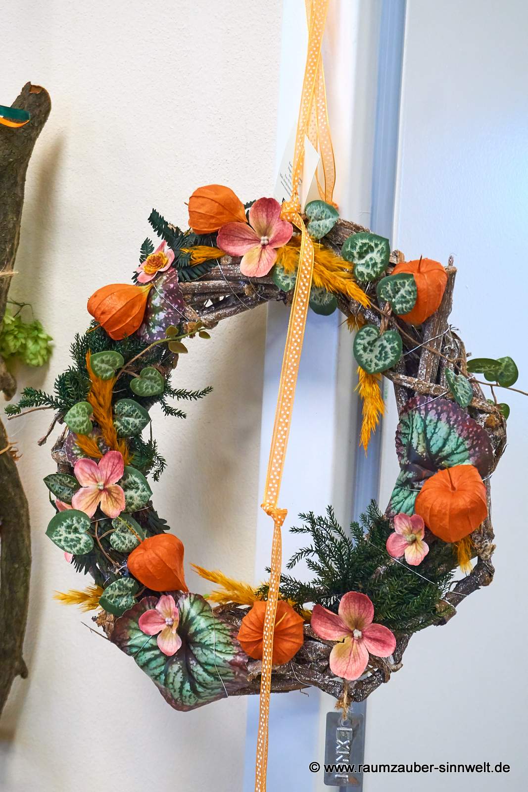 Herbstlicher Wandkranz aus Naturmaterialien und Seidenblüten.