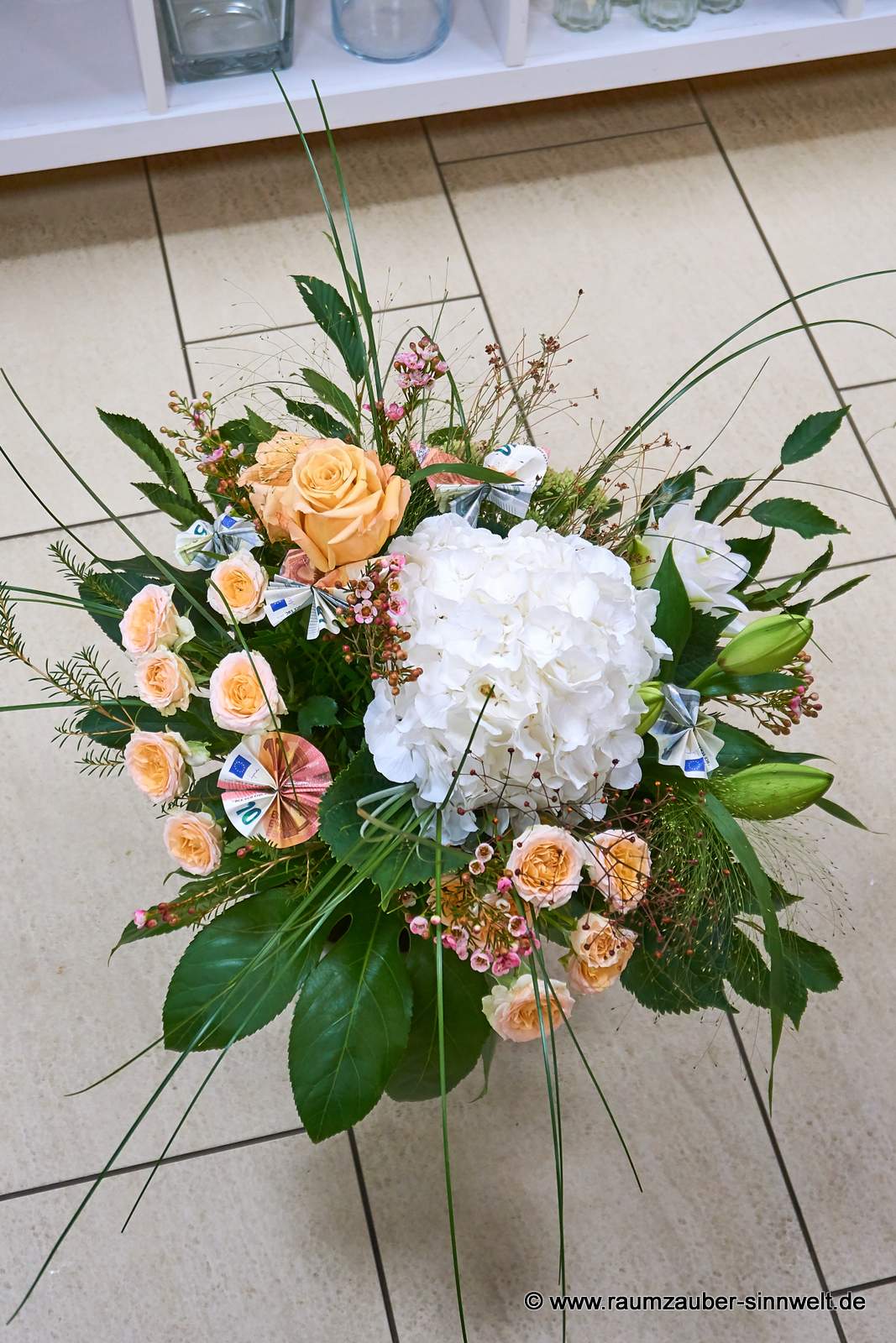 Geldpräsent in Rundstrauß aus Hortensie, Rosen, Lilien und Wachsblümchen