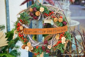 Trauerkranz zum Gedenken mit farbigen Exoten und Rostschild