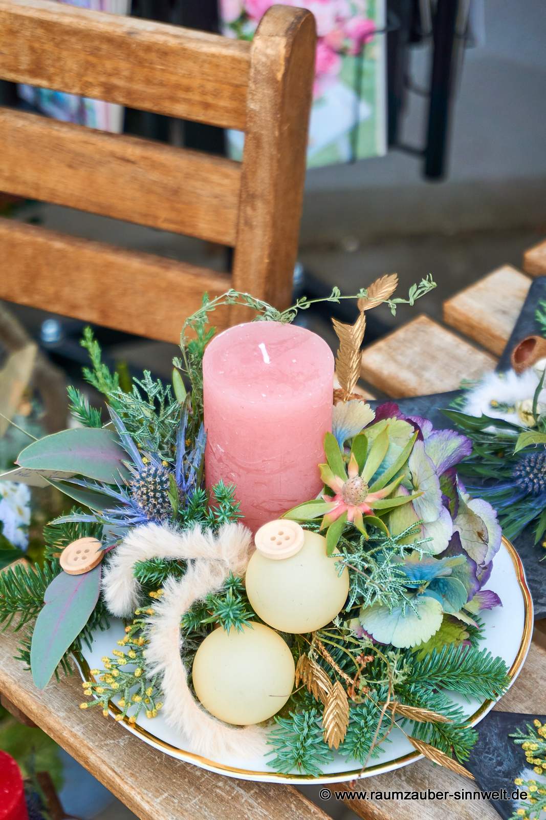 Handgefertigtes Adventsgesteck aus Naturmaterialien und Kugeln auf Keramikteller mit Kerze weihnachtlich dekoriert.