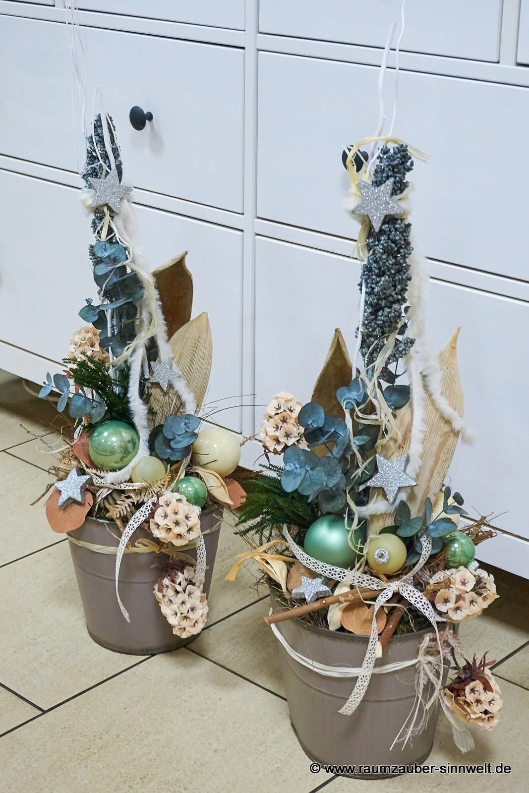 Weihnachtsdekorationen aus Naturmaterialien, Seidenblüten und Kugeln im Keramikgefäß mit LED-Lichterkette