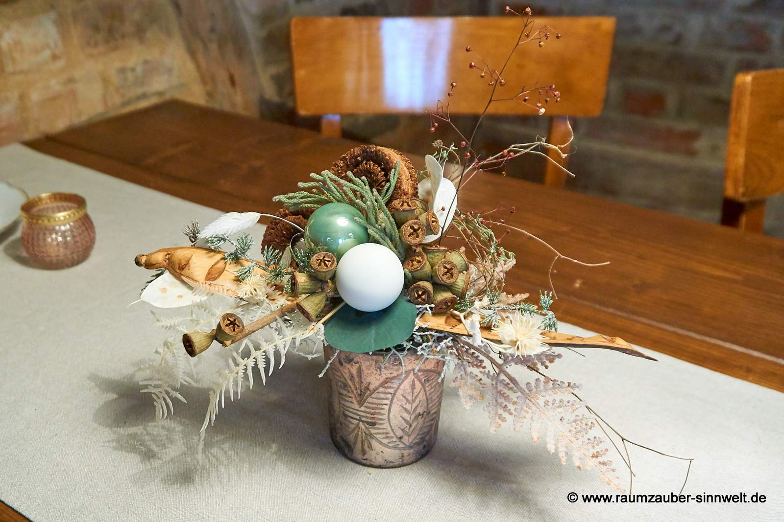 Winterliche Tischdekoration aus Naturmaterialien und Kugeln im Glasgefäß.