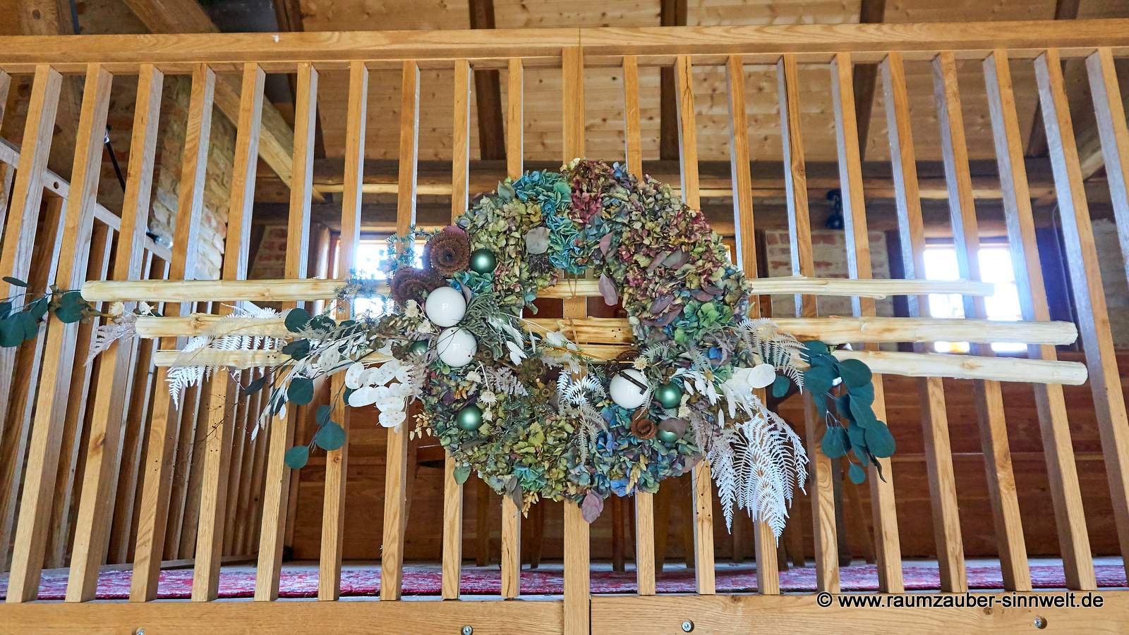 Getrockneter Hortensienkranz und Kugeln mit winterlicher Dekoration.