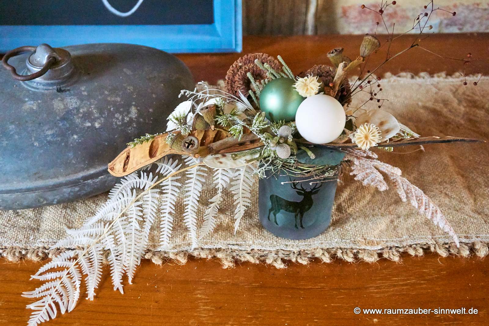 Winterliche Tischdekoration aus Naturmaterialien und Kugeln im Glasgefäß.