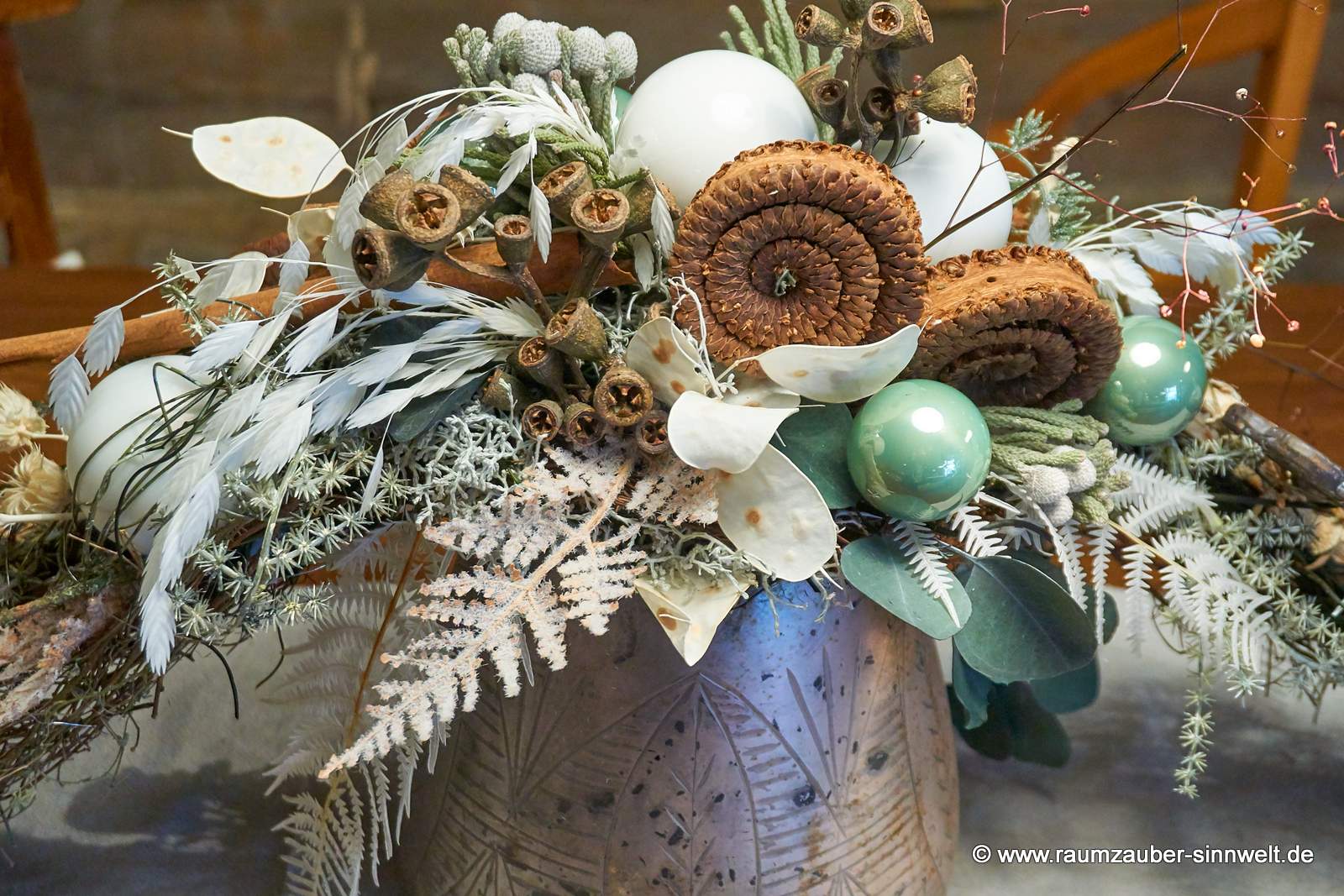 Winterliche Tischdekoration aus Naturmaterialien und Kugeln im Glasgefäß.