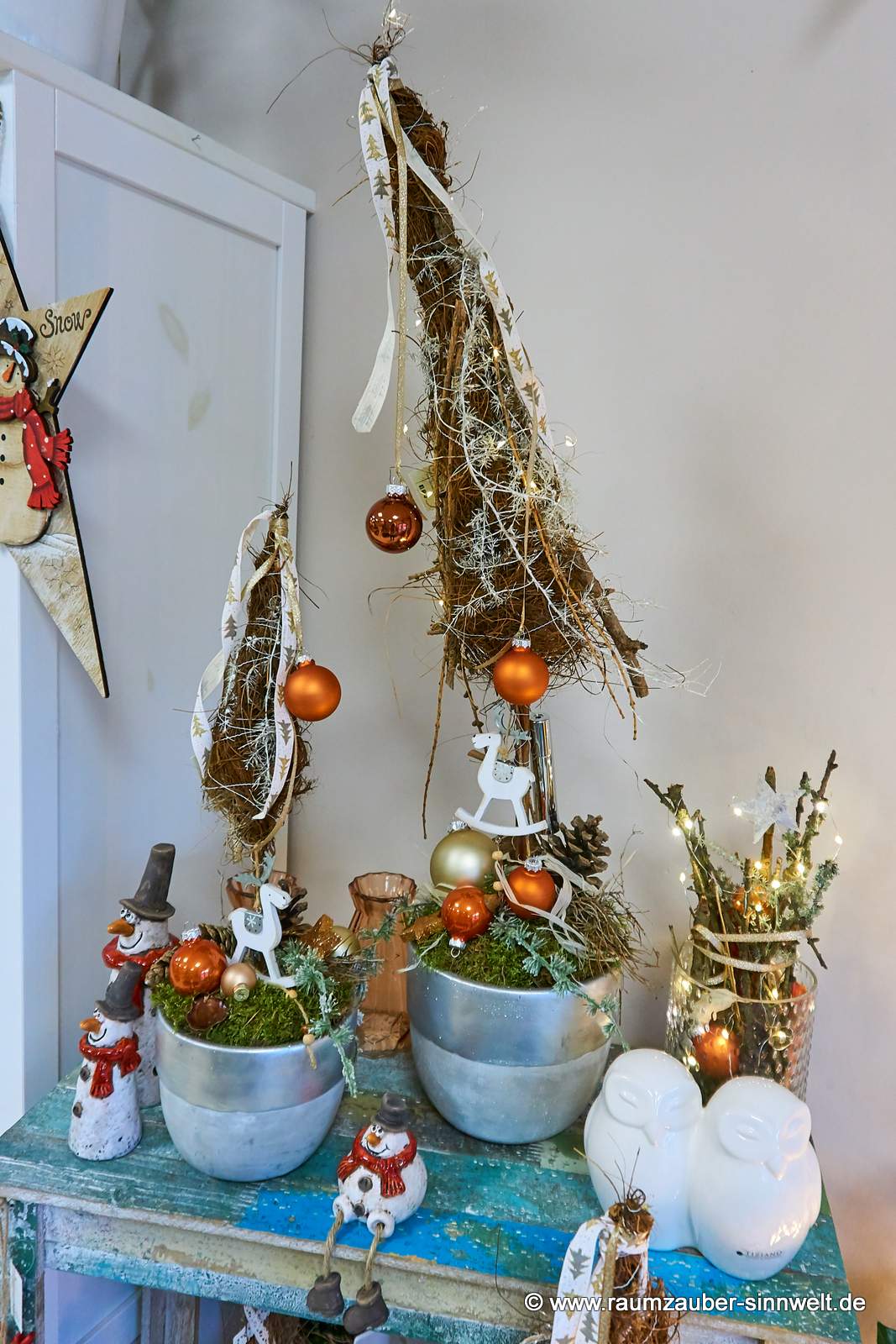 Weihnachtsdekorationen aus Naturmateriealien und Kugeln im Keramikgefäß mit LED-Lichterkette und Deko-Figuren