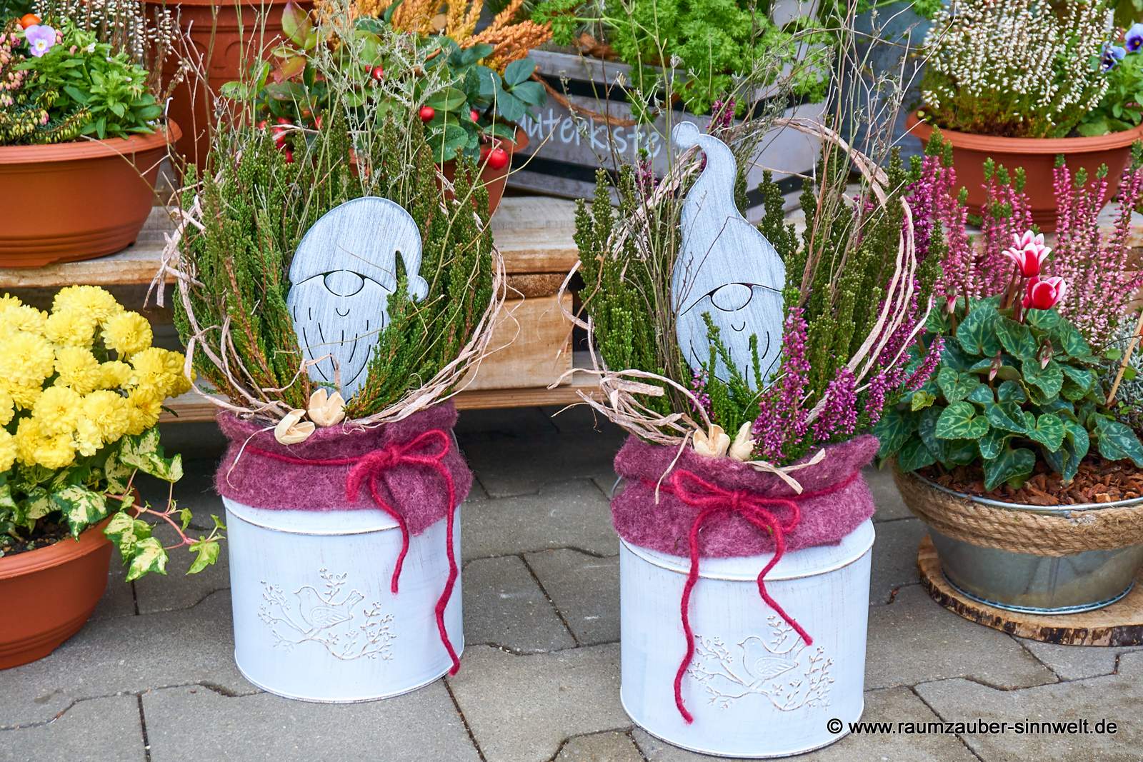 Einpflanzungen mit Heide und Blech-Weihnachtsmann winterlich dekoriert im Blechgefäß.