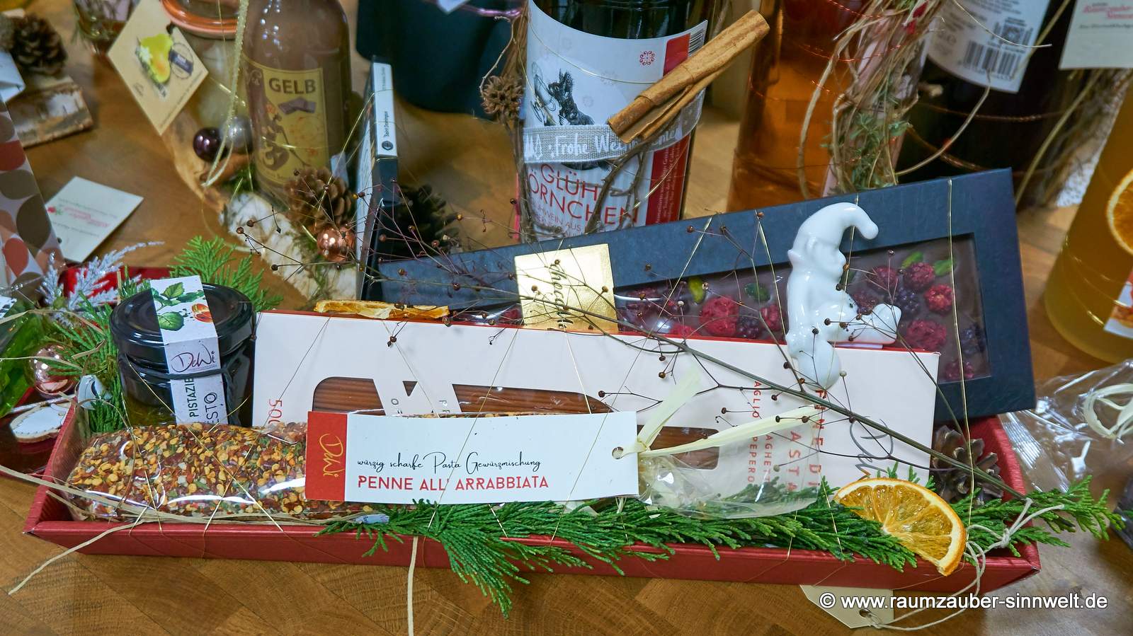Präsentkorb gefüllt mit Pasta, Pesto und Gewürzmischung aus italienischer Feinkostmanufaktur, Schokolade von chocoMe und Weihnachtsfigur von Tiziano weihnachtlich dekoriert.