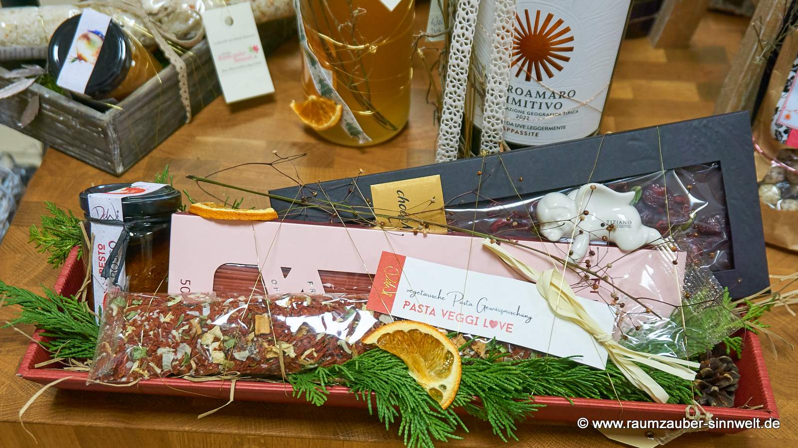 Präsentkorb gefüllt mit Pasta, Pesto und Gewürzmischung aus italienischer Feinkostmanufaktur, Schokolade von chocoMe und Weihnachtsfigur von Tiziano weihnachtlich dekoriert.
