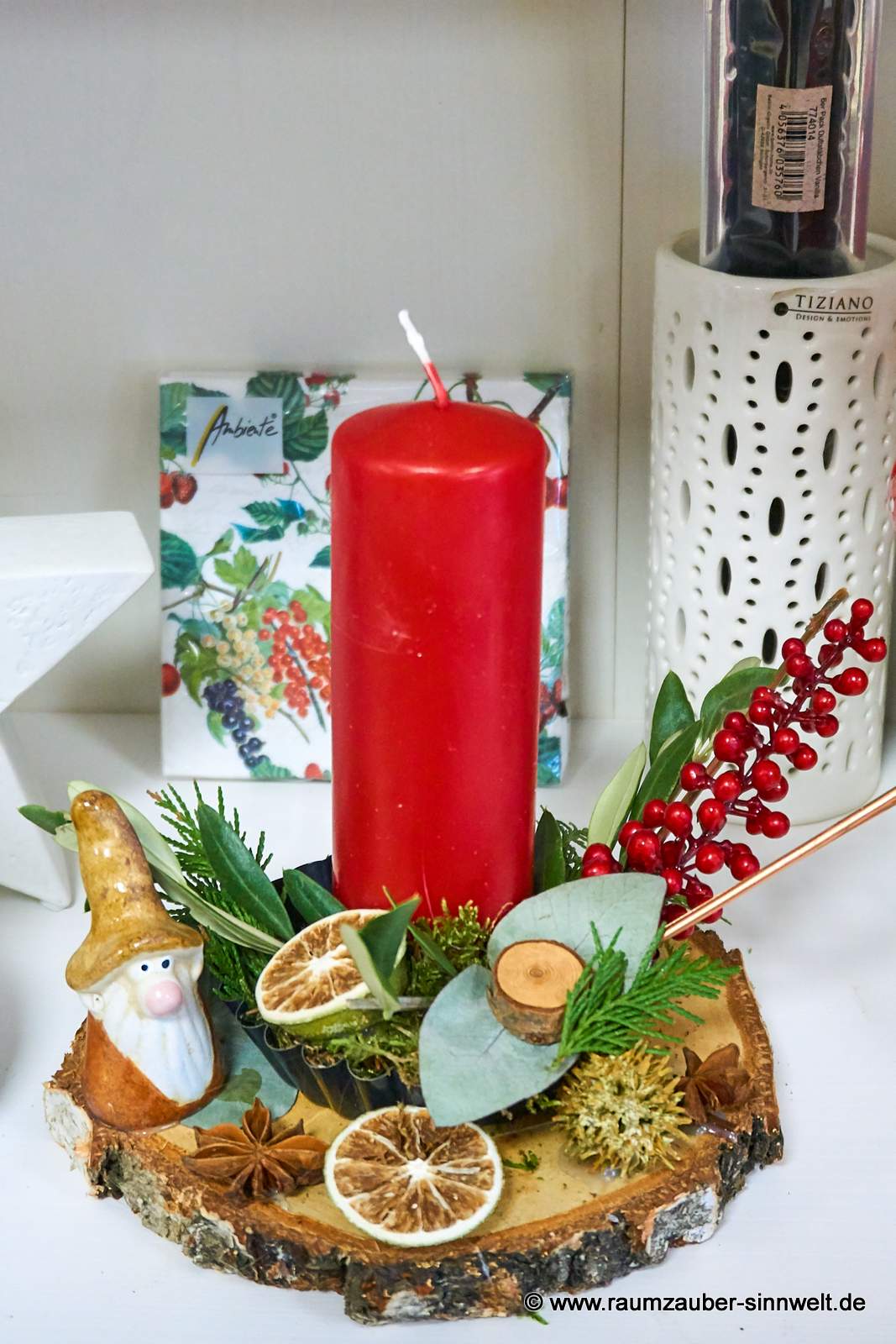 Handgefertigtes Adventsgesteck aus Naturmaterialien auf Holzscheibe mit Kerze und Wichtel weihnachtlich dekoriert.