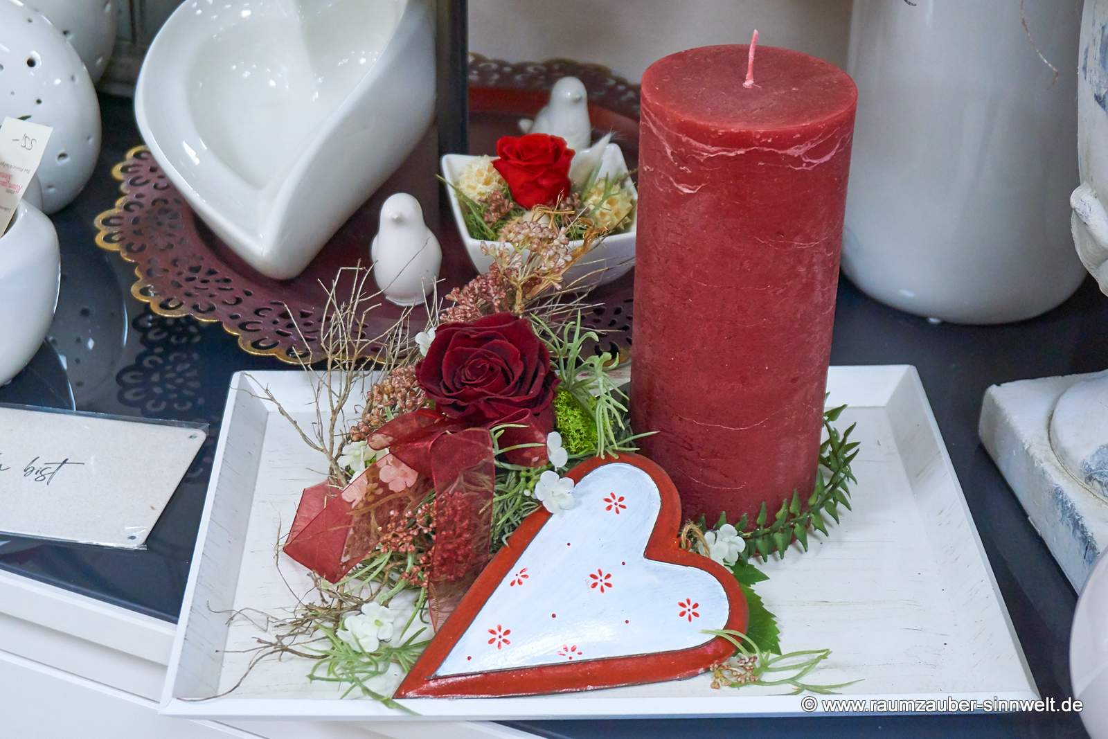 Gefriergetrocknete Rose, Kerze und Deko-Blechherz auf Tablet dekoriert.