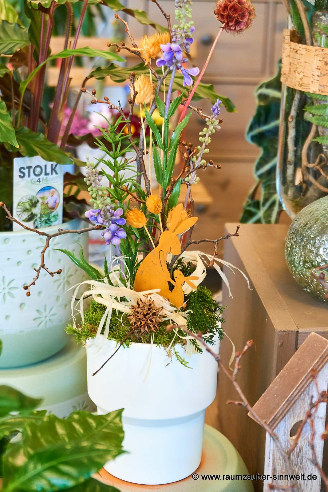 Österliches Seidenblumengesteck mit Rosthasen in Keremikgefäß.