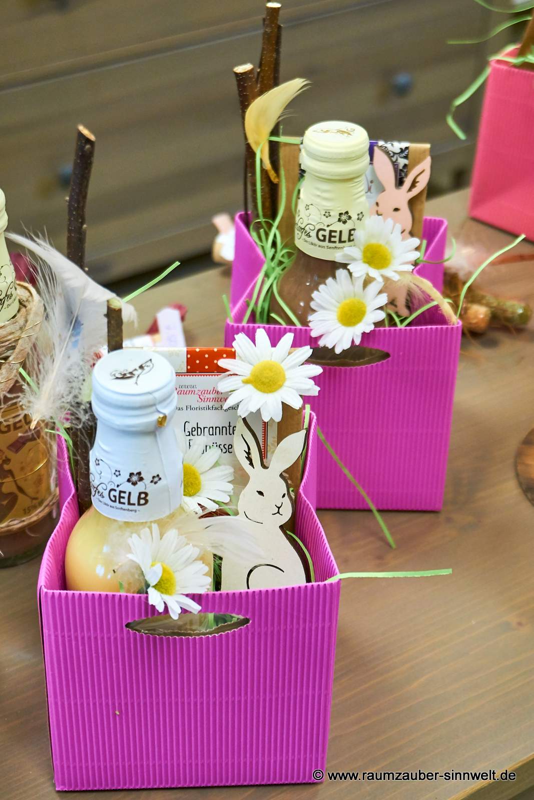 Präsente mit Likör "Scharfes Gelb", Schokofrüchten und Dekohase österlich dekoriert.