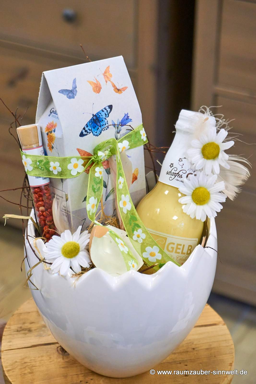 Präsent aus Likör "Scharfes Gelb", naturbelassenem Tee vom Grätz-Verlag und Gewürzröhrchen in Keramikschale Cosmo von Tiziano österlich dekoriert