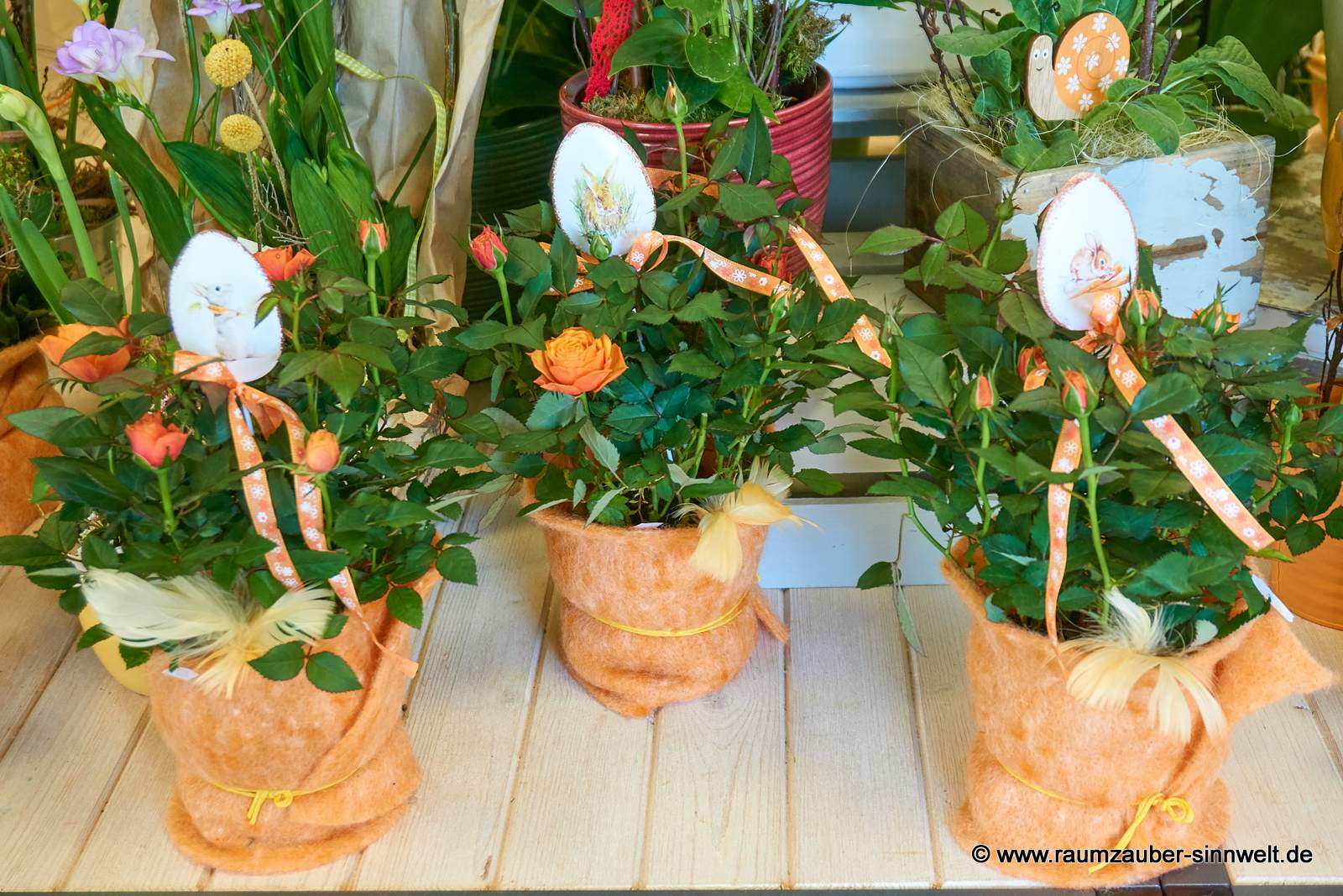 Minirosen mit Filzmanschette und Dekostecker dekoriert.