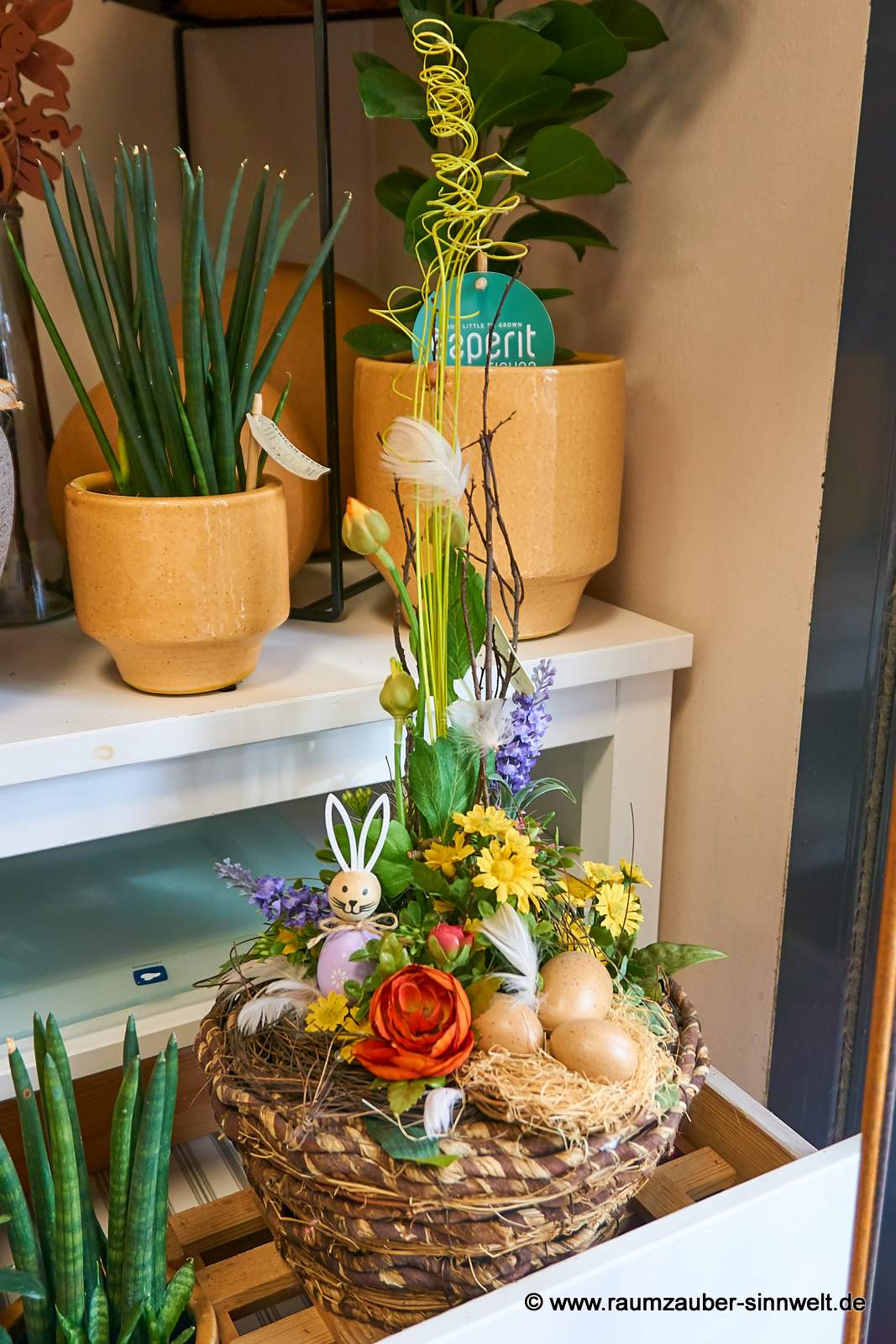 Große Osterdekoration aus Seidenblumen mit Dekohasen und Ostereiern im Korbgefäß