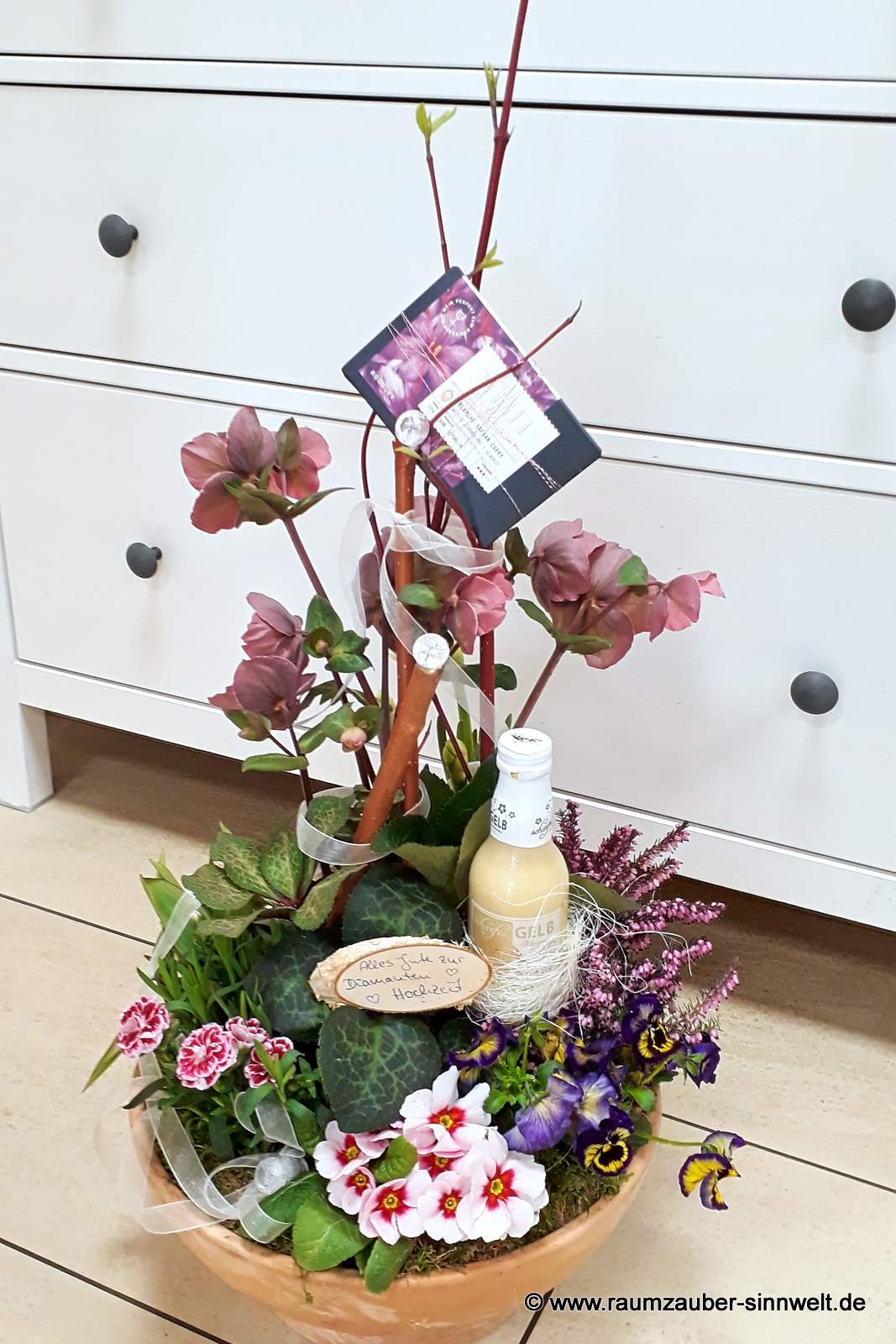 Präsent zur Diamantenen Hochzeit aus Christrosen, Primeln, Nelken, Heide mit Likör "Scharfes Gelb" und Schokolade aus der SCHELL Schokoladenmanufaktur