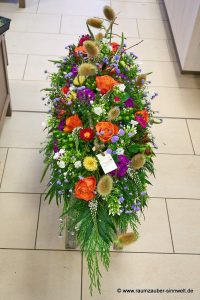 Sargschmuck aus Rosen, Astern, Phlox, Disteln und Wiesenblüten