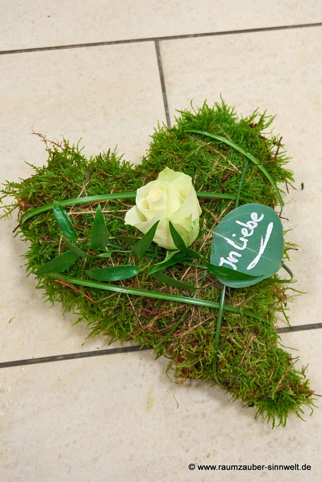 Moosherz für den Bestattungswald mit weißer Rose und beschriebenem Blatt