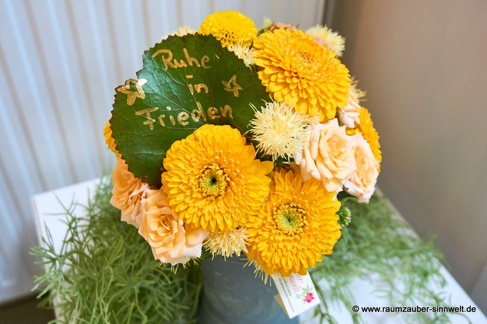 Blütenkugel für den Ruhewald aus Rosen, Gerbera und beschriebenem Blatt.