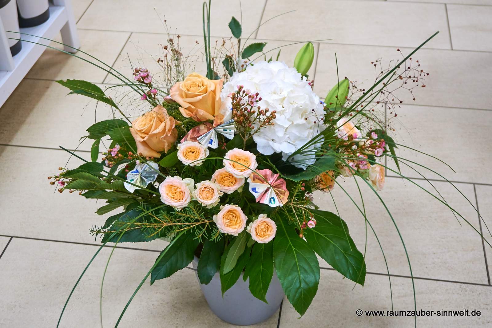 Geldpräsent in Rundstrauß aus Hortensie, Rosen, Lilien und Wachsblümchen