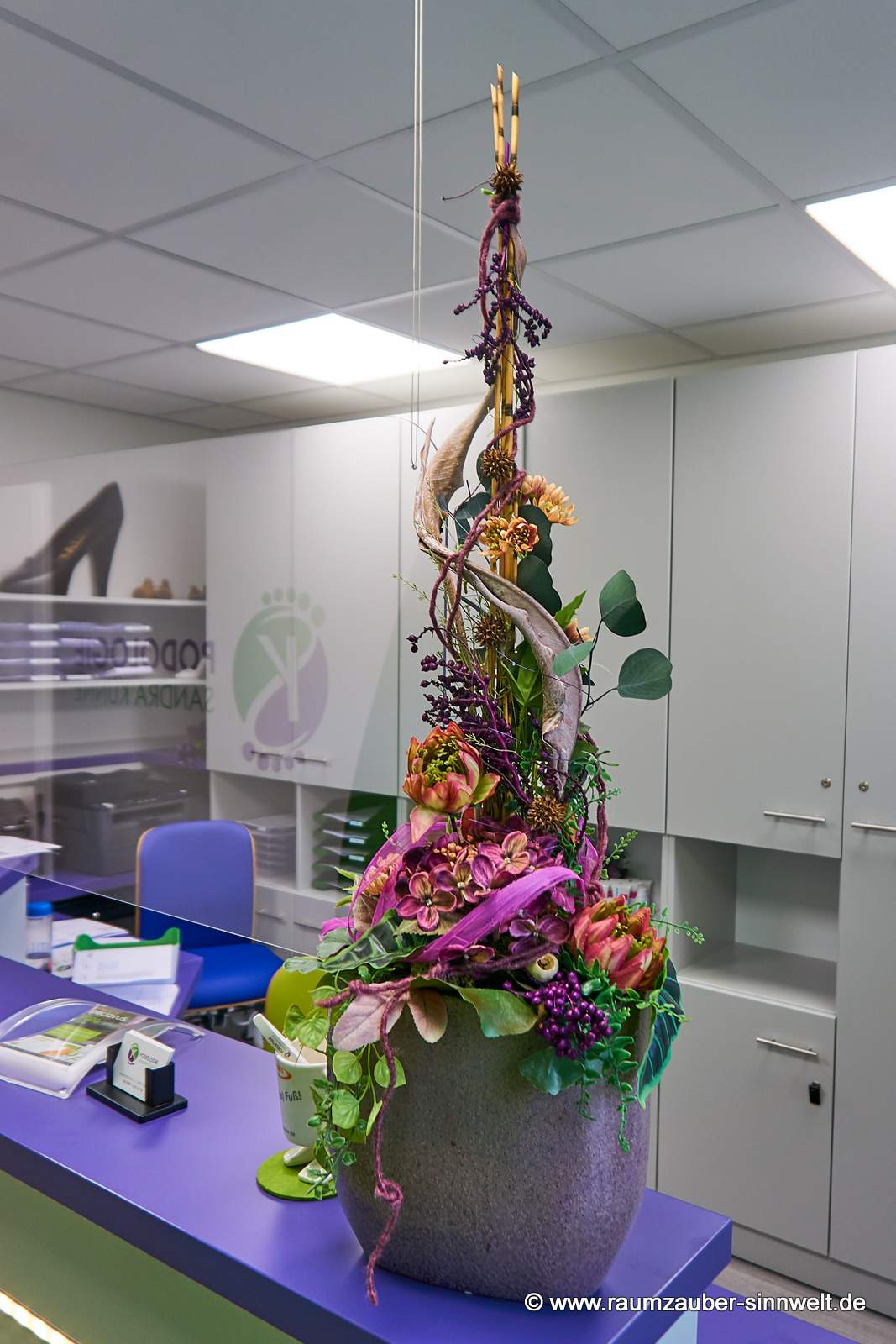 Handgefertigtes Gesteck aus Seidenblumen, Naturmaterialien und gefriergetrockneten Rosen als Praxisdekoration