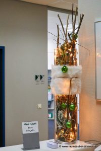 Weihnachtliche handgefertigte Seidenblumendekoration mit Naturmaterialien und LED-Lichterkette im Glasgefäß