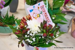 Tischgesteck aus Alstromerien, Santini und Schleierkraut mit Malbuch zum Schulanfang dekoriert