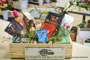Großer Präsentkorb mit Produkten kleiner Feinkostmanufakturen: Pasta, herzhafte Snacks, Pesto, Wein aus der Pfalz, Likör "Scharfes Gelb", Brotbackmischung, Pasta-Gewürzmischungen, Kaffee aus sächsischer Kaffeerösterei, naturbelassener Tee vom Grätz-Verlag, Gewürzröhrchen, handgeschöpfte Schokolade von chocoMe und Vintage-Dekoschild.